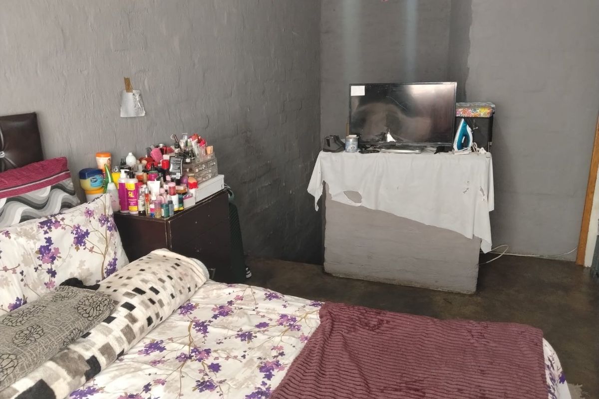 A bedroom featuring painted brick walls and concrete flooring, requiring cosmetic updates to improve the overall finish and aesthetic appeal.