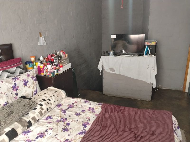 A bedroom featuring painted brick walls and concrete flooring, requiring cosmetic updates to improve the overall finish and aesthetic appeal.