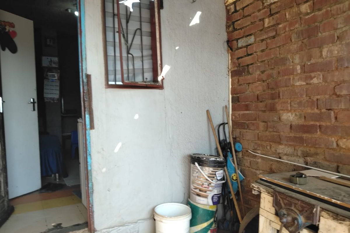 A utility area featuring exposed brickwork and a window with security bars, requiring maintenance and cosmetic updates to improve its overall condition.