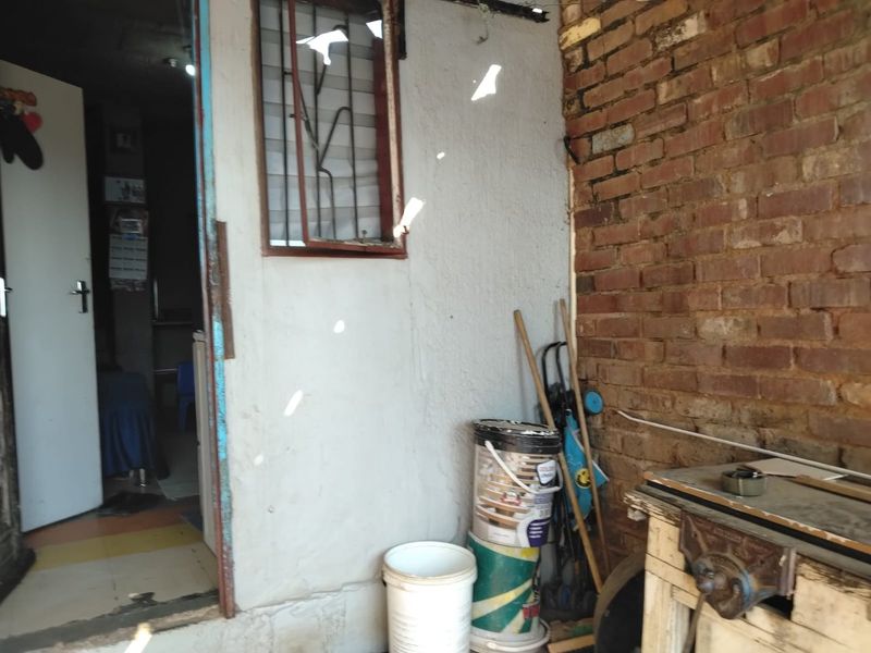 A utility area featuring exposed brickwork and a window with security bars, requiring maintenance and cosmetic updates to improve its overall condition.
