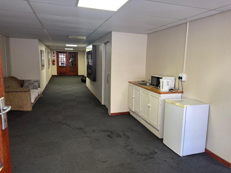 Commercial hallway featuring a drop ceiling, carpeted flooring, and a small built-in kitchenette area with sink and cabinetry.