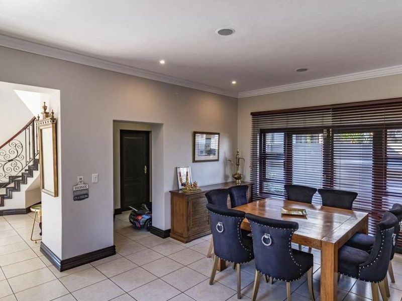 A well-maintained dining area featuring tiled flooring, recessed lighting, and a staircase with a decorative wrought iron balustrade.