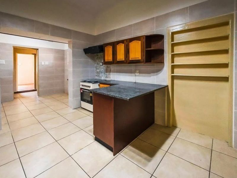 A functional kitchen featuring tiled walls and flooring, built-in cabinetry, and a freestanding stove, offering a clean, blank canvas for potential modern updates.