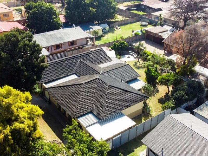 Aerial view of the property showcasing the tiled roof structure, surrounding garden, and perimeter fencing within a residential neighborhood.