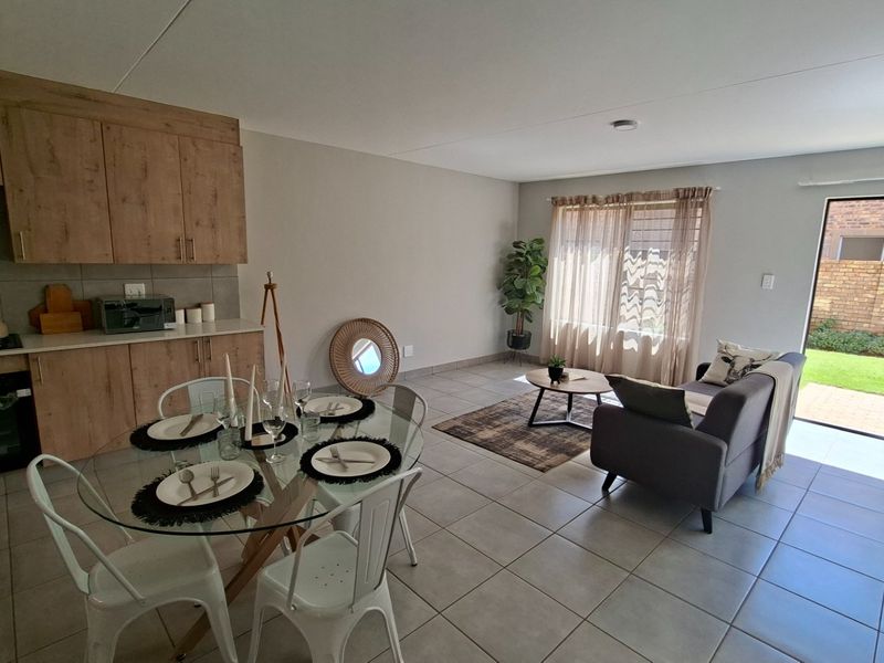 Open-plan living area featuring a modern kitchen with wood-finish cabinetry, tiled floors, and a sliding door leading to the rear garden.