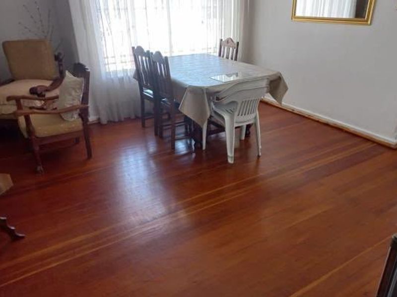 A dining area featuring polished hardwood flooring and a large window, providing a bright and functional space for meals.