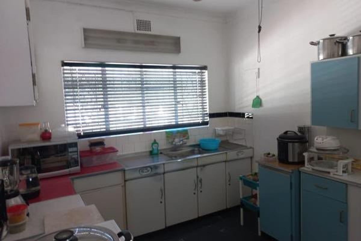 A functional kitchen featuring dated cabinetry, a stainless steel sink, and tiled splashbacks, offering potential for modernization and renovation.