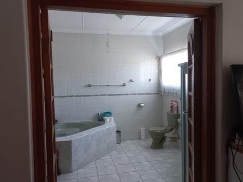A functional bathroom featuring a corner bathtub, tiled walls, and floor, providing a clean and practical space.