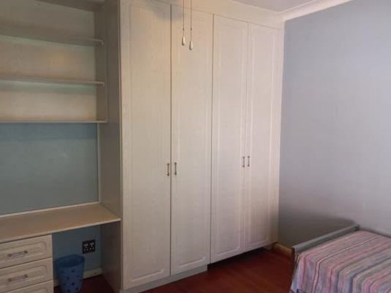Bedroom featuring built-in cupboards, a integrated desk area with shelving, and laminate flooring.