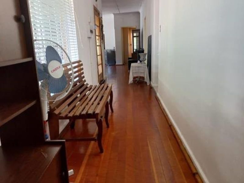 A long interior hallway featuring polished hardwood flooring and timber door frames, providing access to the various rooms of the home.
