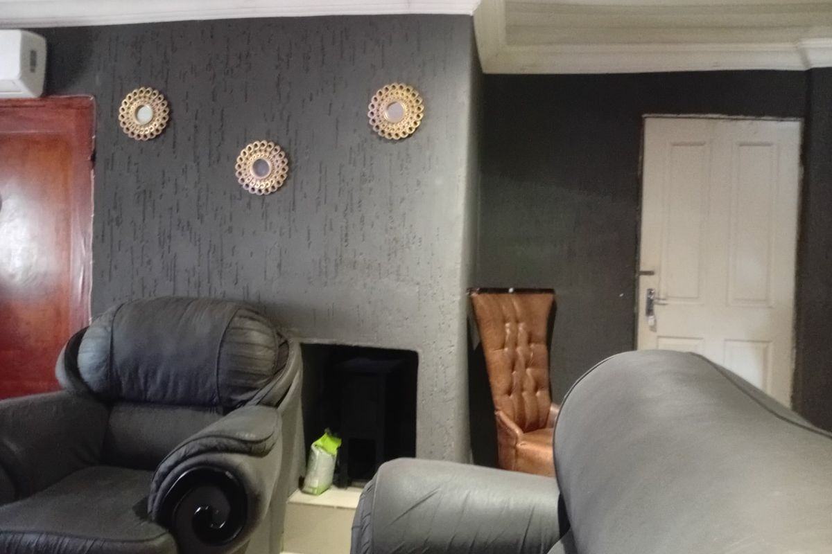 A living room featuring a dark textured feature wall with a built-in fireplace, cove ceiling detailing, and an installed air conditioning unit.