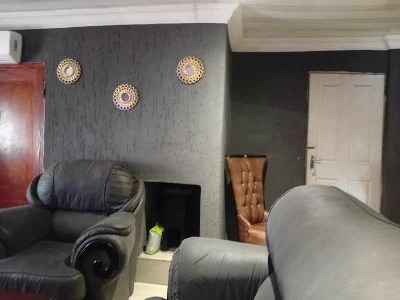 A living room featuring a dark textured feature wall with a built-in fireplace, cove ceiling detailing, and an installed air conditioning unit.