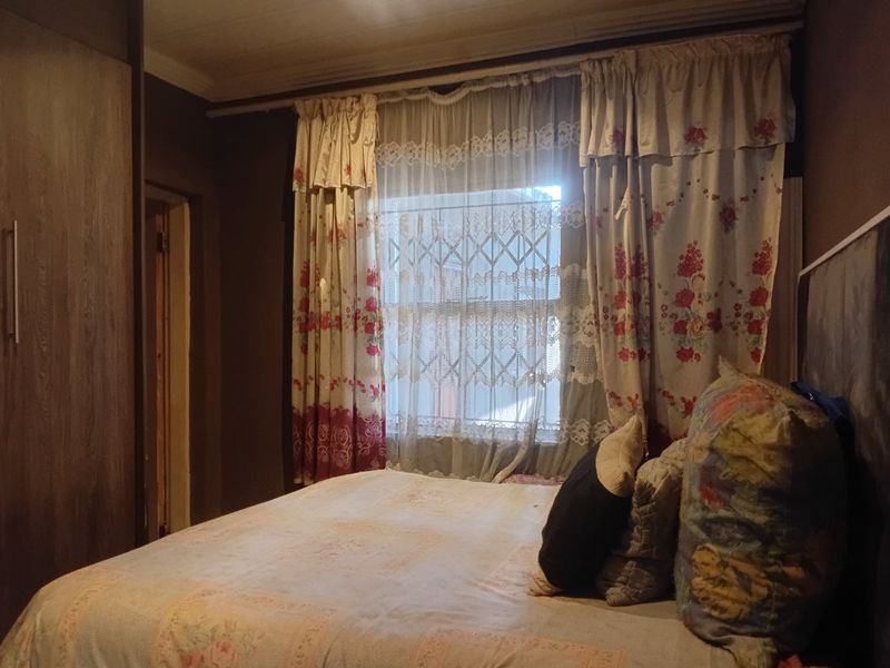 A bedroom featuring built-in cupboards and a window fitted with a security gate.