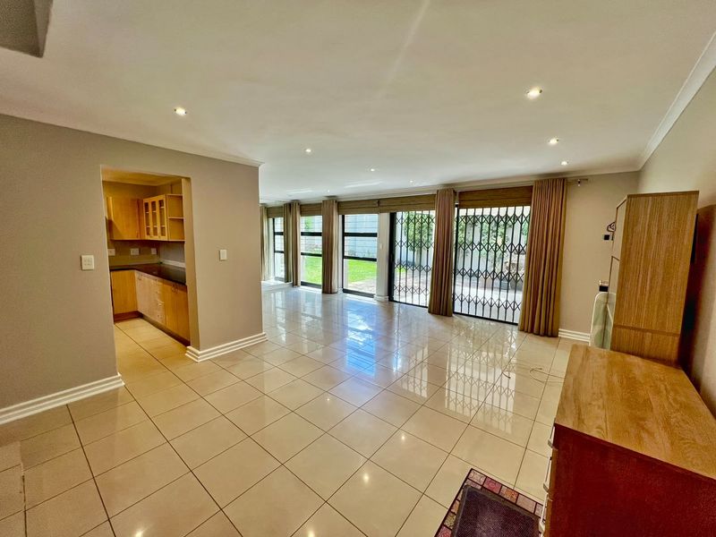 Spacious open-plan living area featuring polished tile flooring, recessed lighting, and direct access to a private patio through large sliding glass doors.