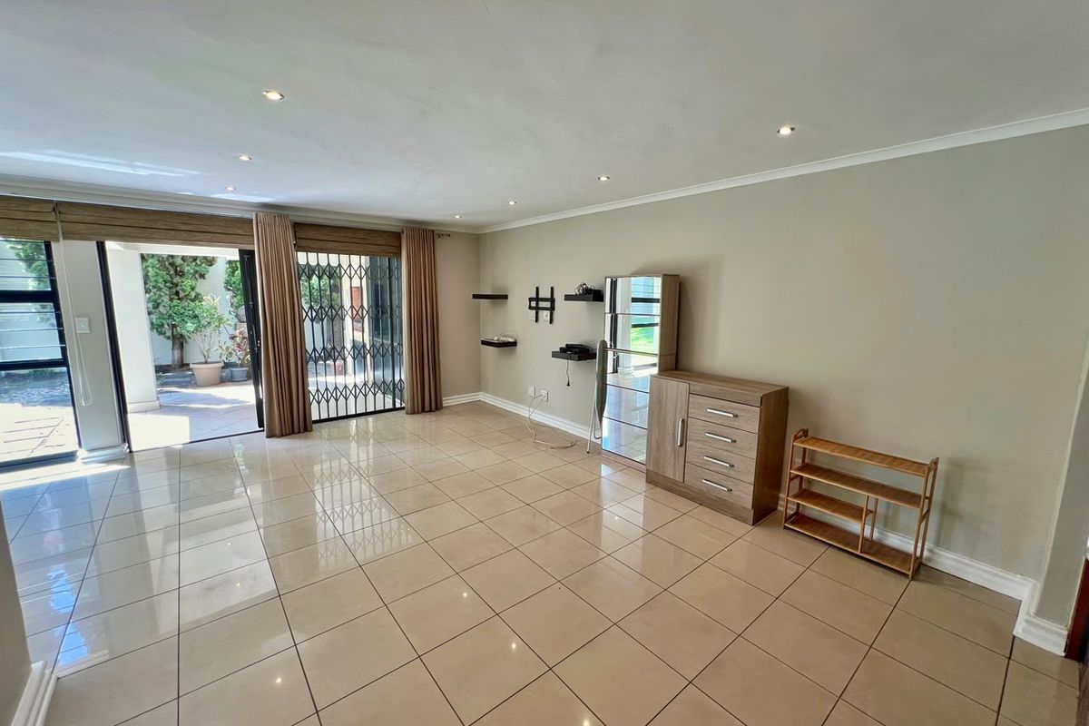 Spacious living area featuring large format floor tiles, recessed downlighting, and a sliding glass door providing direct access to the outdoor patio.