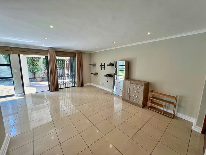 Spacious living area featuring large format floor tiles, recessed downlighting, and a sliding glass door providing direct access to the outdoor patio.