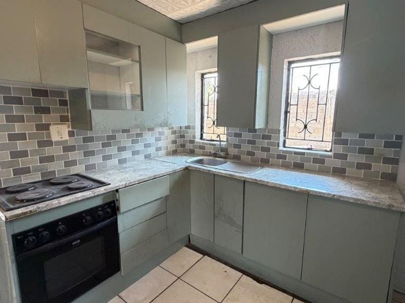 A functional kitchen featuring built-in cabinetry, laminate countertops, a built-in oven with electric hob, and a tiled backsplash.