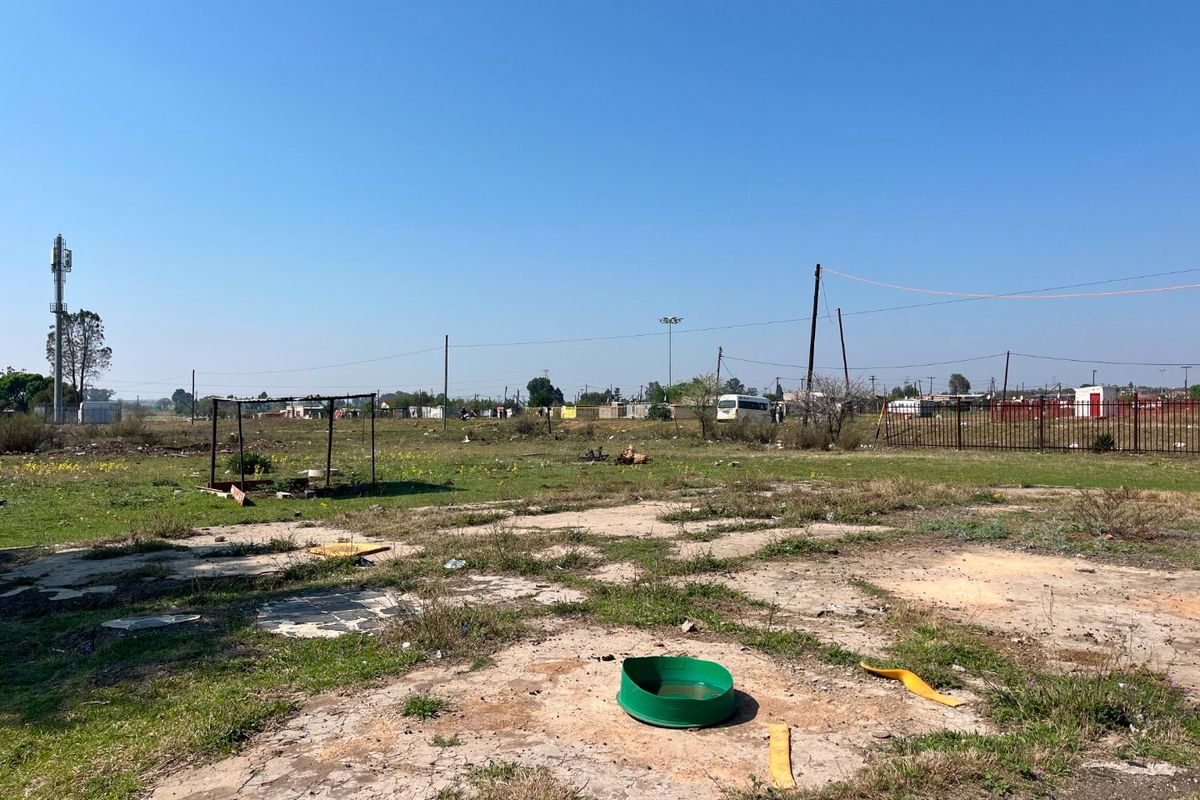 A large, undeveloped plot of land featuring a cracked concrete slab foundation, perimeter fencing, and open field space suitable for future development.