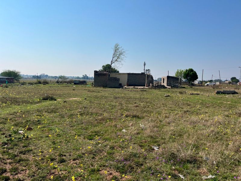A view of a large plot of land featuring a dilapidated, partially collapsed masonry structure in need of significant repair or demolition.