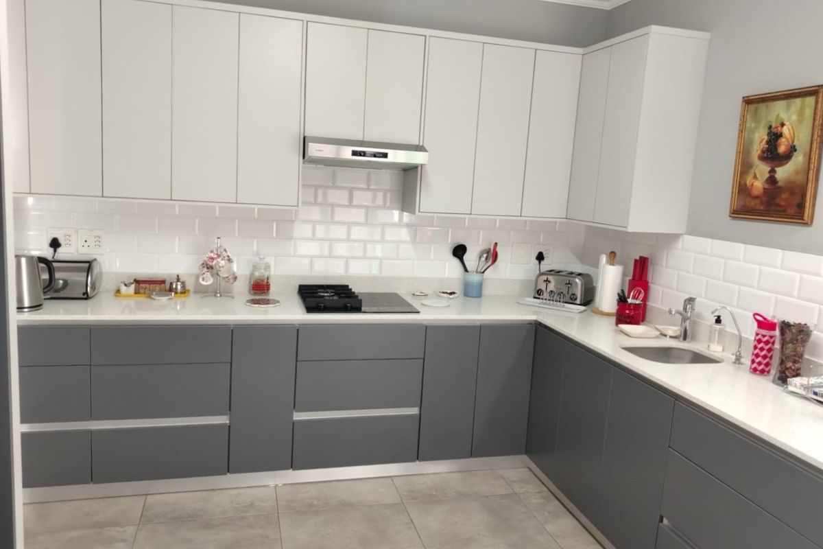 Modern kitchen featuring two-tone cabinetry, quartz countertops, subway tile backsplash, integrated gas hob, and extractor fan with high-quality finishes.