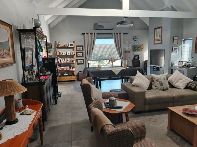 Spacious open-plan living and dining area featuring vaulted ceilings with exposed beams, tiled flooring, and a built-in fireplace.