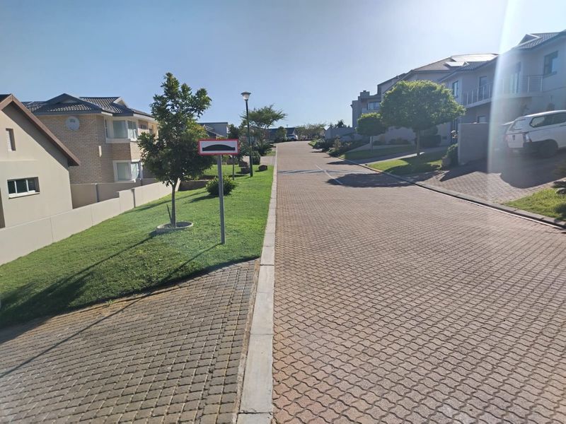 A view of the paved residential street within the estate, featuring well-maintained verges and clear access roads.