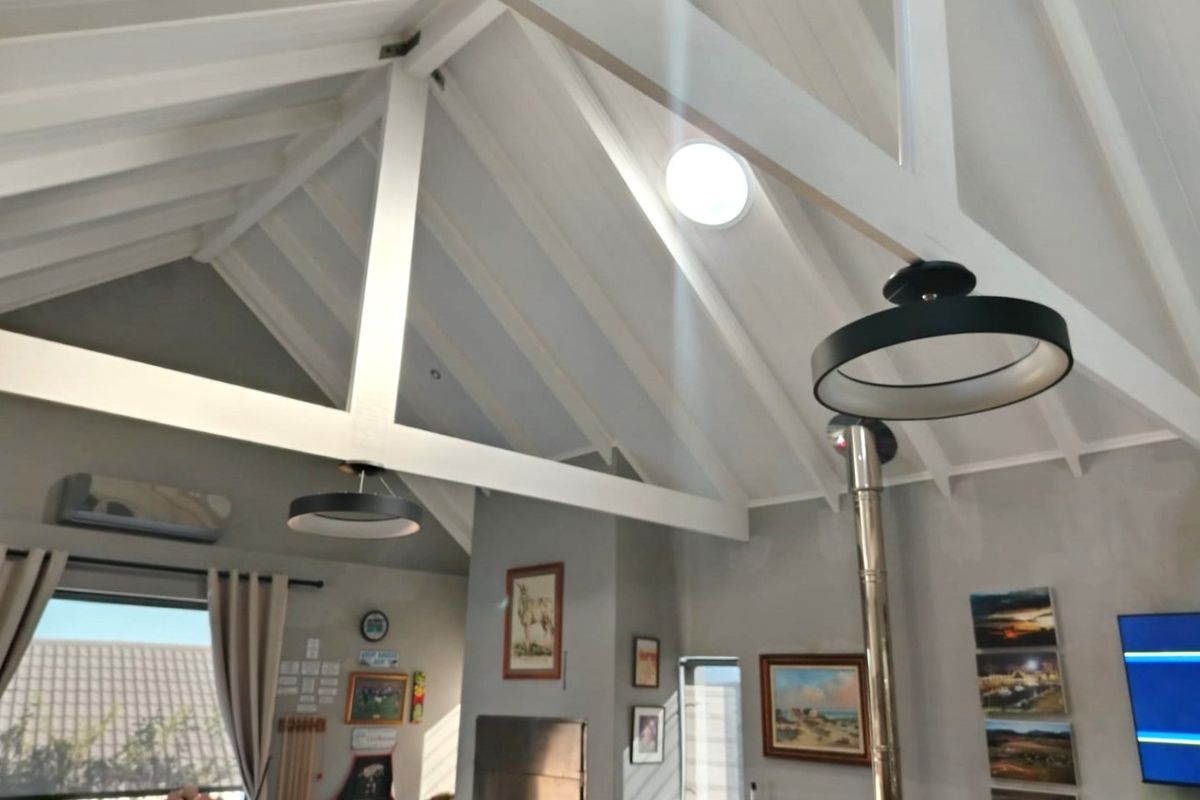 Spacious living area featuring a high vaulted ceiling with exposed timber trusses, a skylight, and a built-in wood burning fireplace.