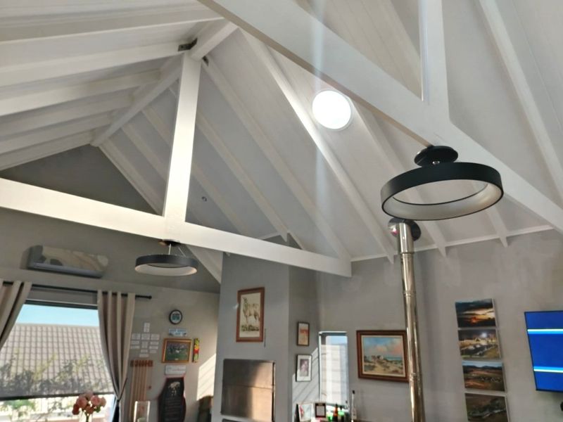 Spacious living area featuring a high vaulted ceiling with exposed timber trusses, a skylight, and a built-in wood burning fireplace.