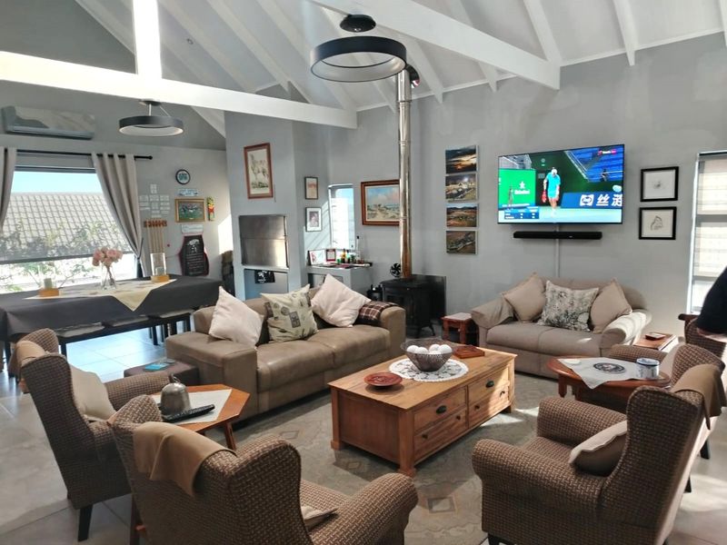 Spacious open-plan living area featuring a vaulted ceiling with exposed beams, a wood-burning fireplace, and a built-in indoor braai.