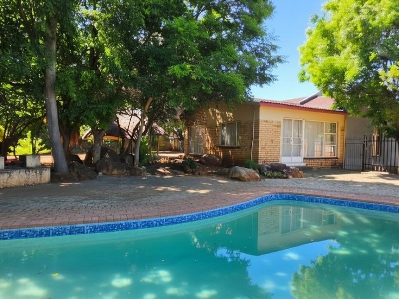 Outdoor pool area featuring a swimming pool, brick paving, and mature trees, providing a private and established garden setting.