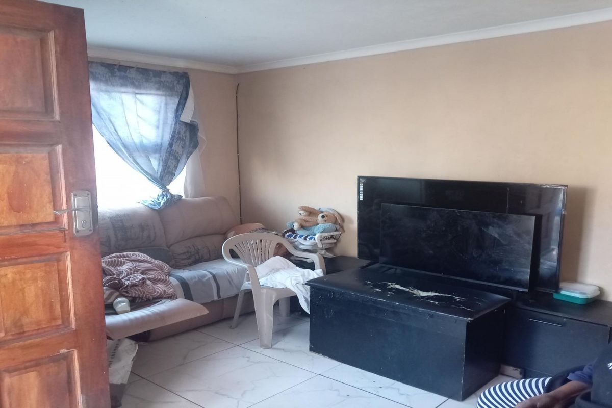 A living room area featuring tiled flooring and a timber door, requiring cosmetic updates to improve the overall aesthetic and condition of the space.