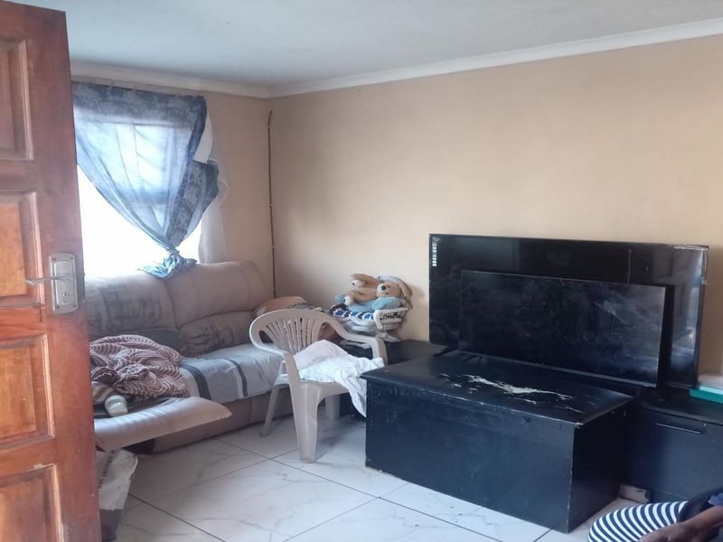 A living room area featuring tiled flooring and a timber door, requiring cosmetic updates to improve the overall aesthetic and condition of the space.