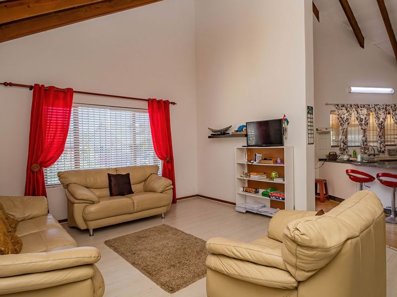 Spacious open-plan living area featuring high vaulted ceilings with exposed timber beams, laminate flooring, and an integrated kitchen with a breakfast bar.