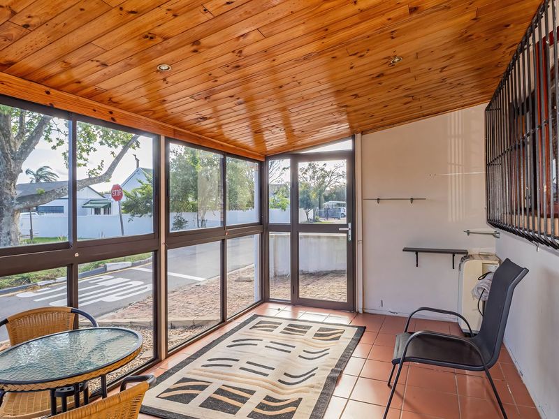 Enclosed patio area featuring a timber ceiling, tiled flooring, and large aluminium-framed windows providing views of the street.