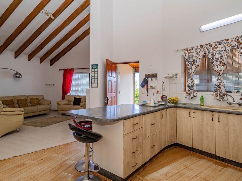 Open plan living area featuring a kitchen with breakfast bar, laminate cabinetry, and vaulted ceilings with exposed timber beams.