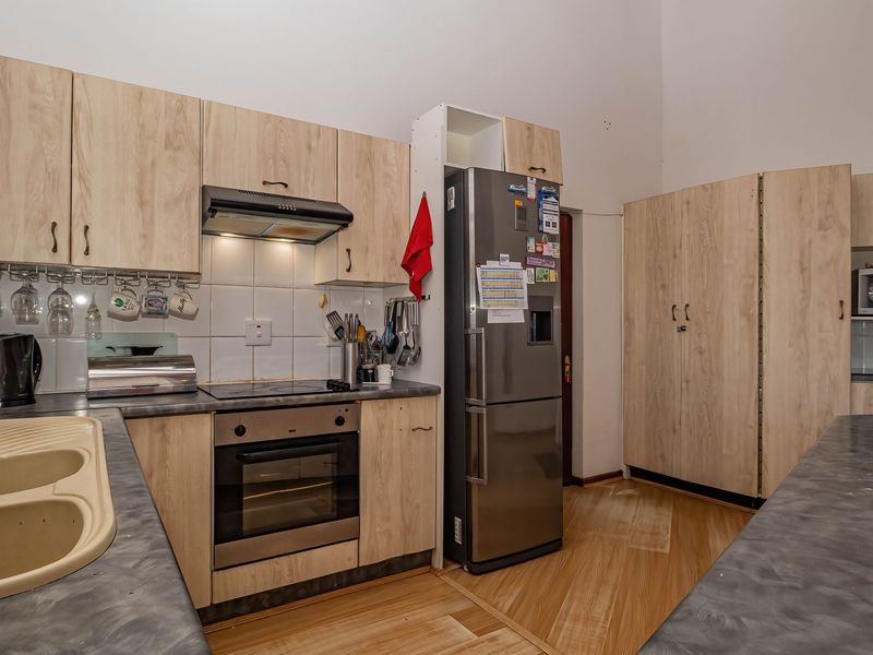 Functional kitchen featuring light wood-look cabinetry, dark laminate countertops, built-in oven with extractor fan, and ample storage space.