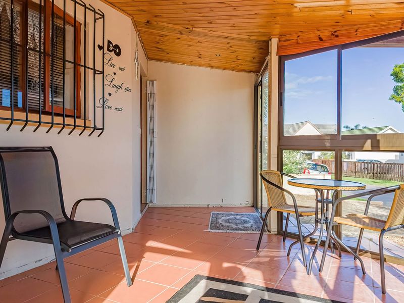 Enclosed patio area featuring tiled flooring, timber ceiling, and large aluminium windows providing natural light and views of the surrounding neighbourhood.