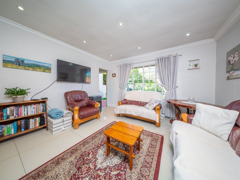 A bright and well-maintained living room featuring tiled flooring, recessed downlighting, and decorative cornicing, offering a comfortable and functional space.