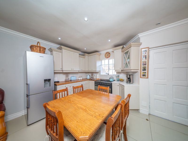 A functional kitchen featuring built-in cabinetry, a gas stove, and tiled flooring, offering a practical layout for daily cooking and dining.