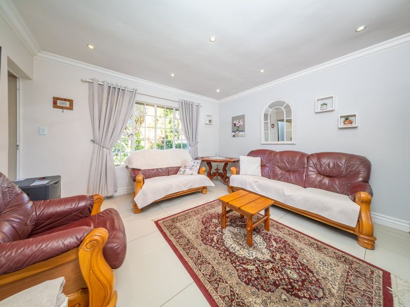 A well-maintained living room featuring neutral tiled flooring, recessed downlighting, and decorative crown molding, providing a bright and comfortable space.