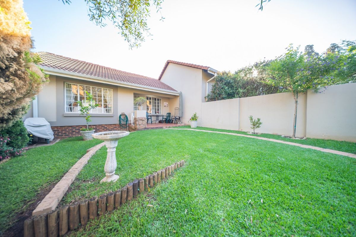 A well-maintained rear garden featuring a manicured lawn, paved patio area, and secure brick boundary walls, offering a private outdoor space.