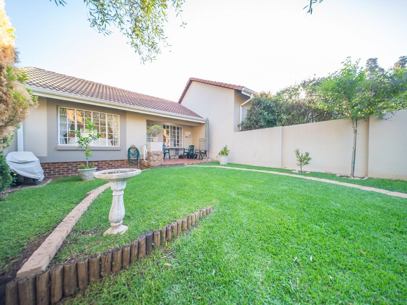 A well-maintained rear garden featuring a manicured lawn, paved patio area, and secure brick boundary walls, offering a private outdoor space.
