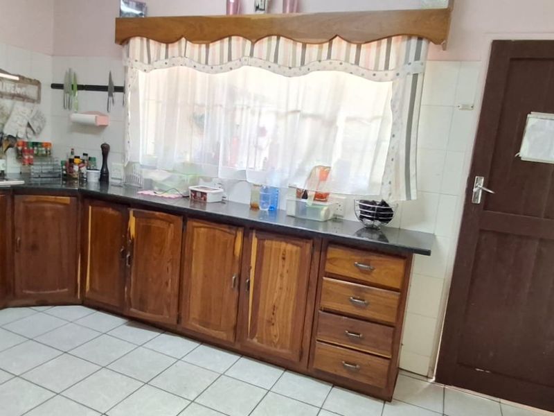 Kitchen featuring wooden cabinetry, granite countertops, gas hob with stainless steel extractor, and tiled flooring. The space offers functional storage and preparation areas.