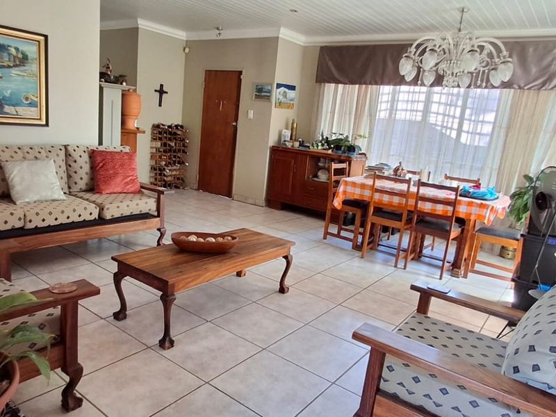 Spacious open-plan living and dining area featuring tiled flooring, beaded ceiling details, and ample natural light.