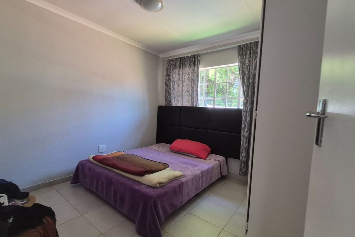 A functional bedroom featuring tiled flooring, neutral wall finishes, and a built-in cupboard, providing a clean and practical living space.