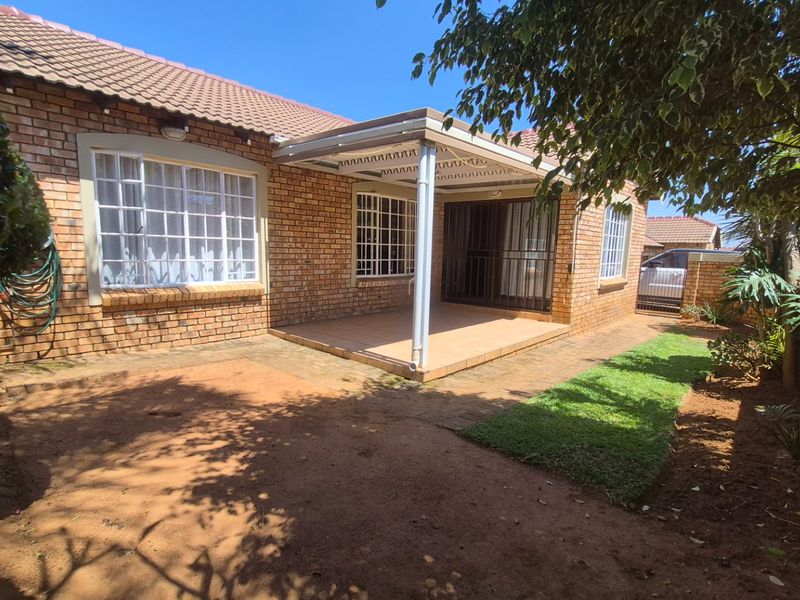 Rear view of the apartment featuring a brick facade, a covered patio area with tiled flooring, and access via sliding glass doors.