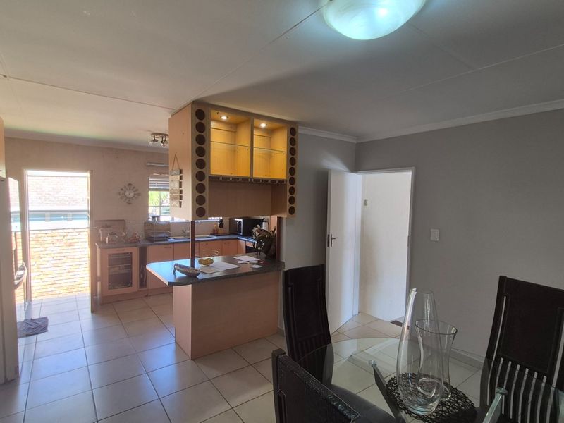 Open-plan kitchen and dining area featuring tiled flooring, built-in cabinetry, and a central kitchen island with integrated storage.