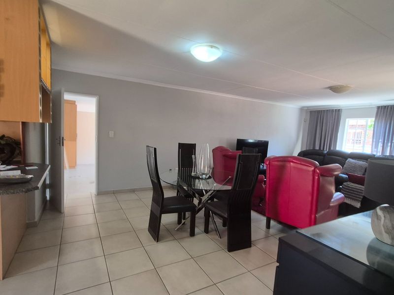 Spacious open-plan living and dining area featuring neutral tiled flooring and a functional kitchen breakfast bar, offering a versatile layout for modern apartment living.