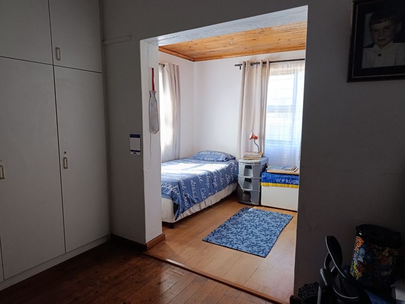 A bedroom featuring built-in cupboards, wooden flooring, and a wooden ceiling, providing a functional space with natural light.