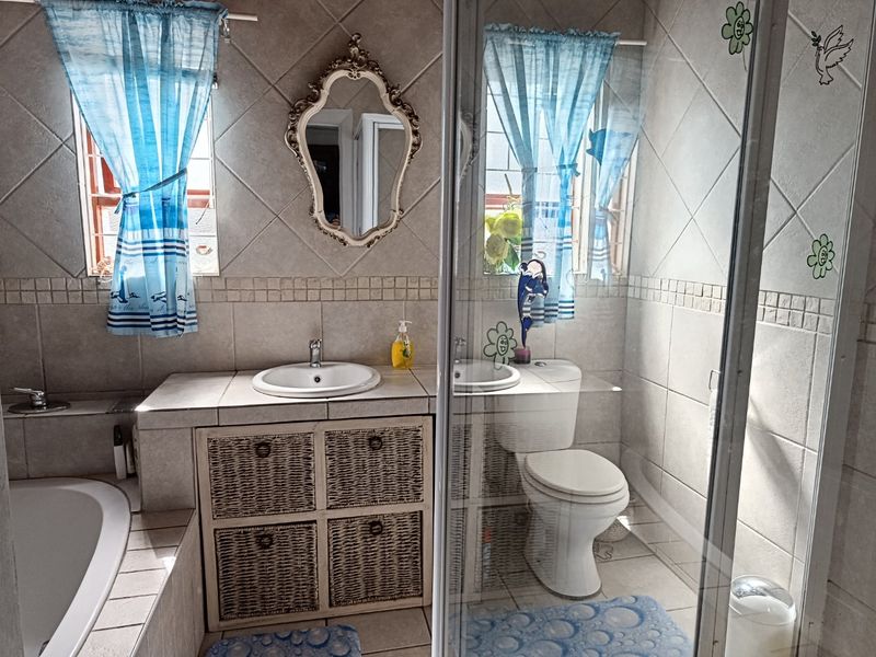 A functional bathroom featuring a built-in vanity with basin, a separate shower enclosure, a toilet, and a tiled bathtub surround.